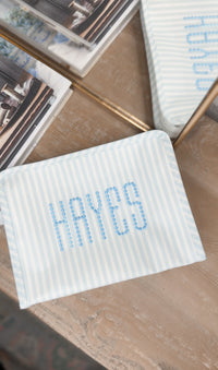 Blue and white striped TRVL Roadie pouch embroidered with 'HAYES' in dotted lettering
