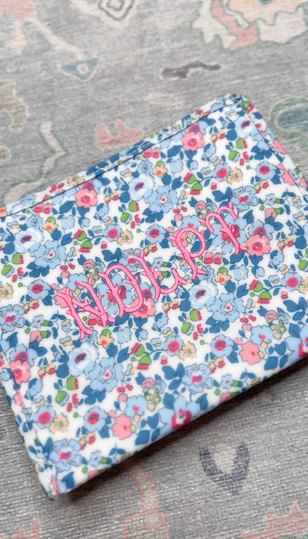 Blue and pink floral TRVL pouch embroidered with a pink name in script