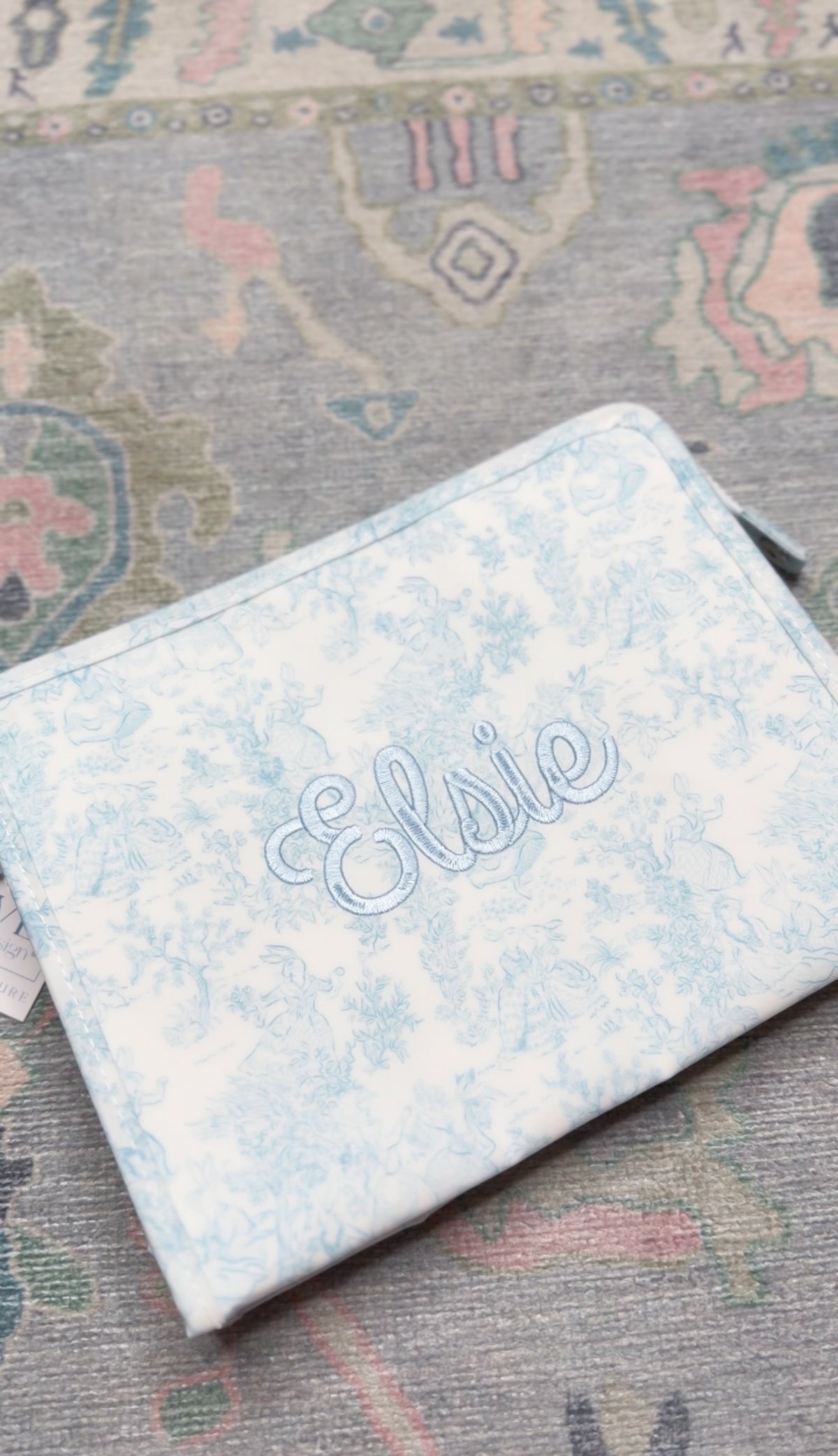 Light blue bunny toile TRVL pouch embroidered with the name 'Elsie' in matching blue script