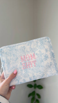 Blue bunny toile TRVL pouch embroidered with pink text reading 'Mom Sh*t'