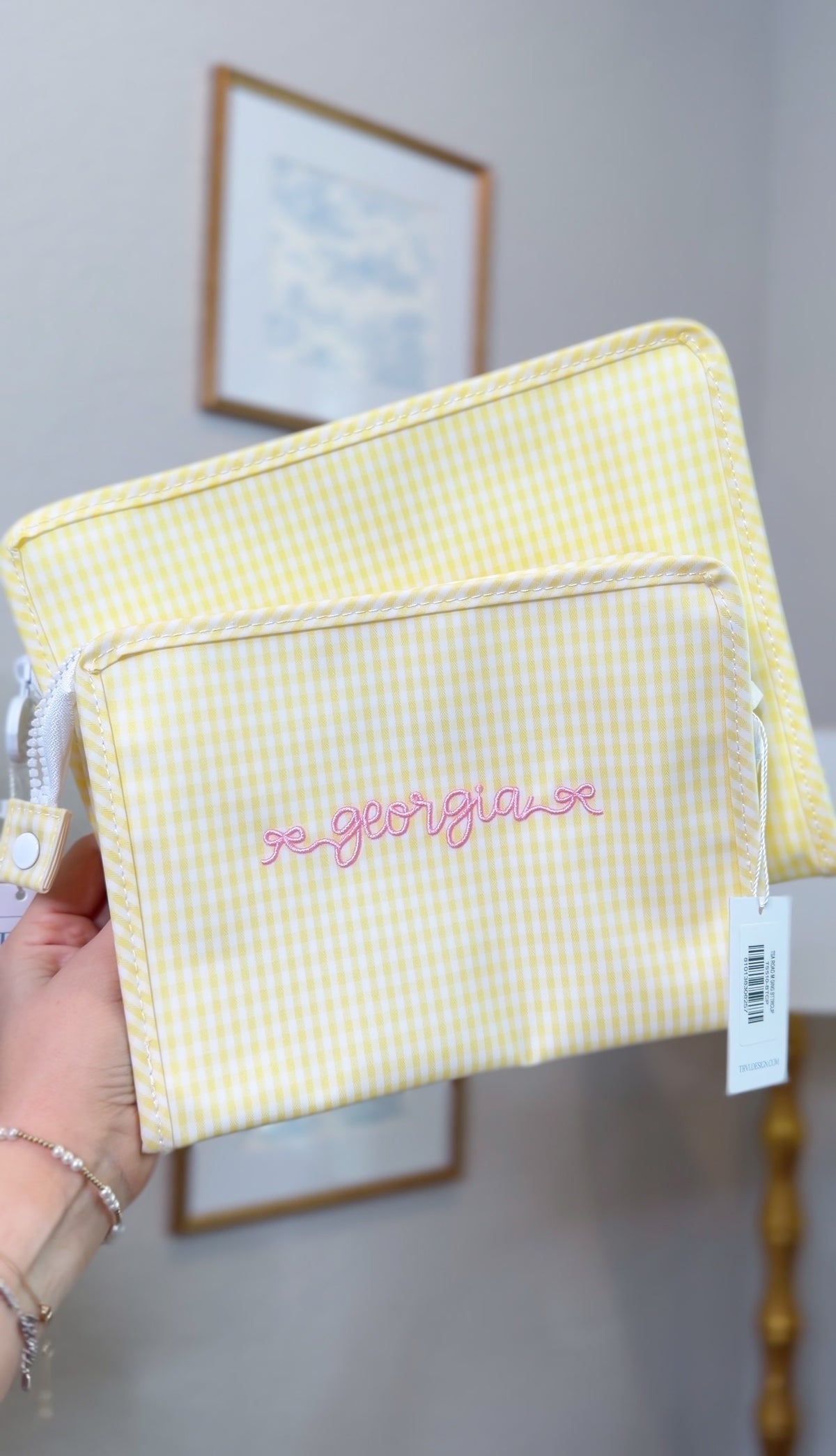 Yellow gingham TRVL pouches, one embroidered with the name 'Georgia' in pink script on a front pocket