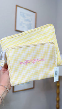 Yellow gingham TRVL pouches, one embroidered with the name 'Georgia' in pink script on a front pocket