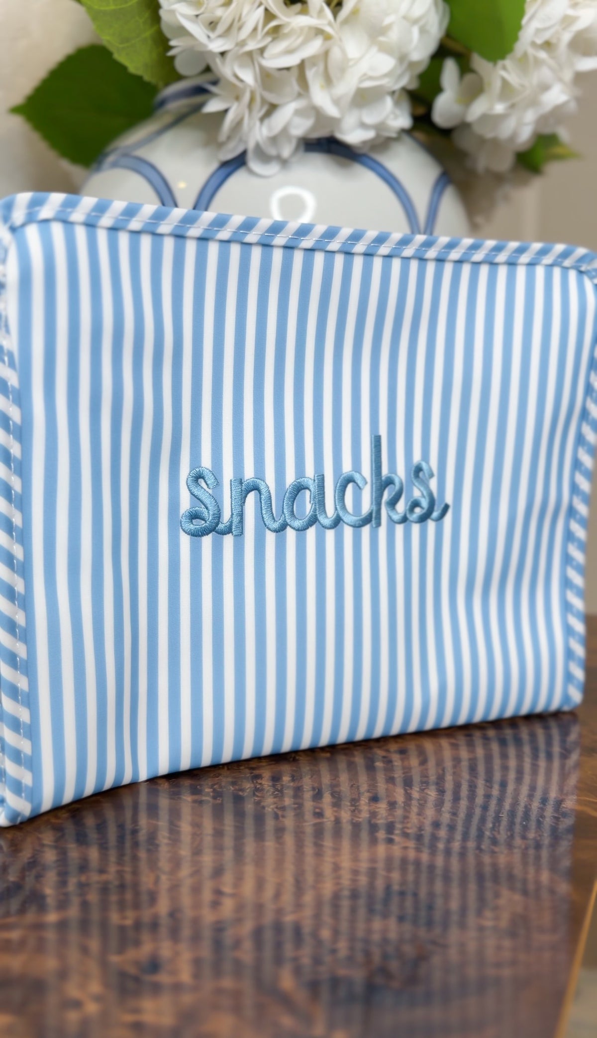 Blue chambray striped TRVL pouch embroidered 'snacks' in blue cursive