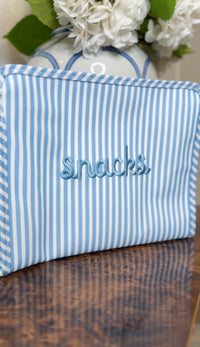 Blue chambray striped TRVL pouch embroidered 'snacks' in blue cursive
