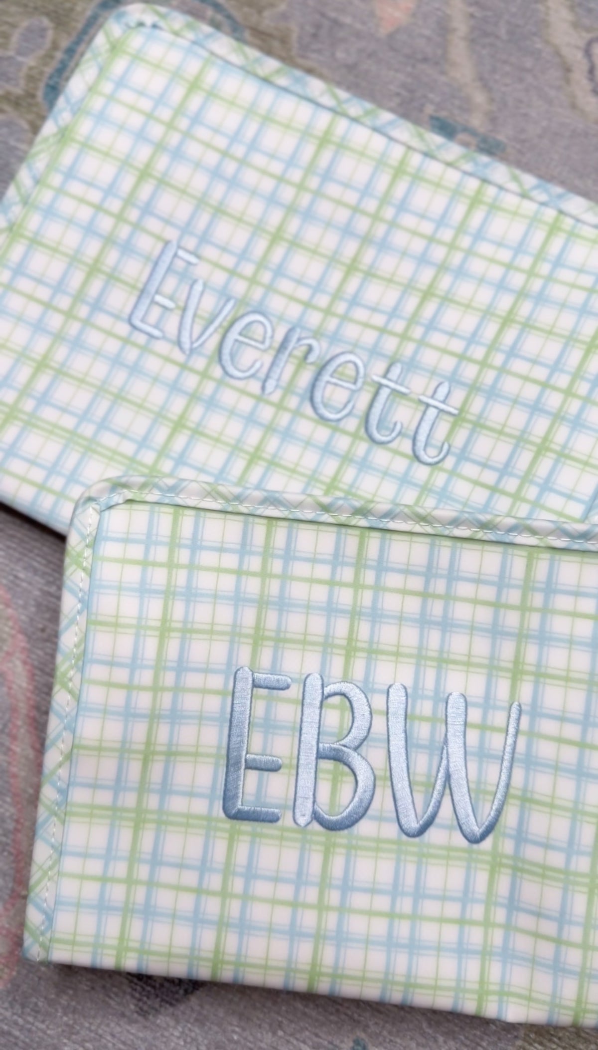Green and blue plaid TRVL pouches embroidered with the name 'Everett' and the 'EBW' monogram