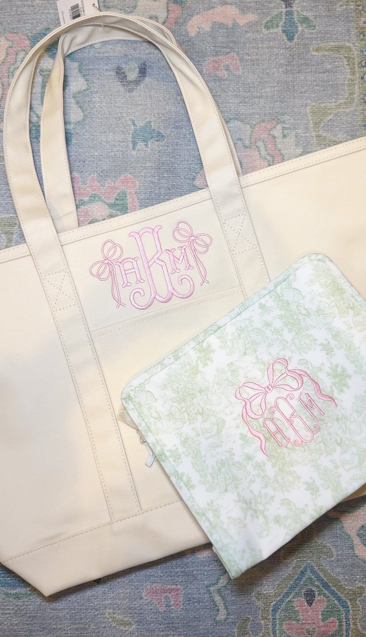 Natural canvas TRVL Maxi Tote and matching pouch, both embroidered with a pink bow monogram