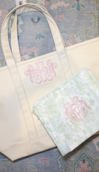 Natural canvas TRVL Maxi Tote and matching pouch, both embroidered with a pink bow monogram
