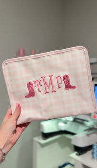 Pink plaid TRVL pouch embroidered with 'TMP' monogram and cowboy boot icons