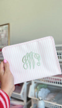Pink Pimlico stripe TRVL Roadie pouch embroidered with an elaborate cursive monogram in green thread