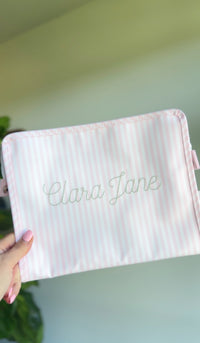 Pink Pimlico stripe TRVL Roadie pouch embroidered with 'Clara Jane' in dotted cursive script