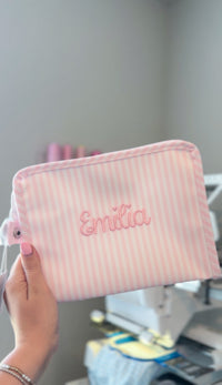 Pink Pimlico stripe TRVL Roadie pouch embroidered with 'Emilia' in cursive script