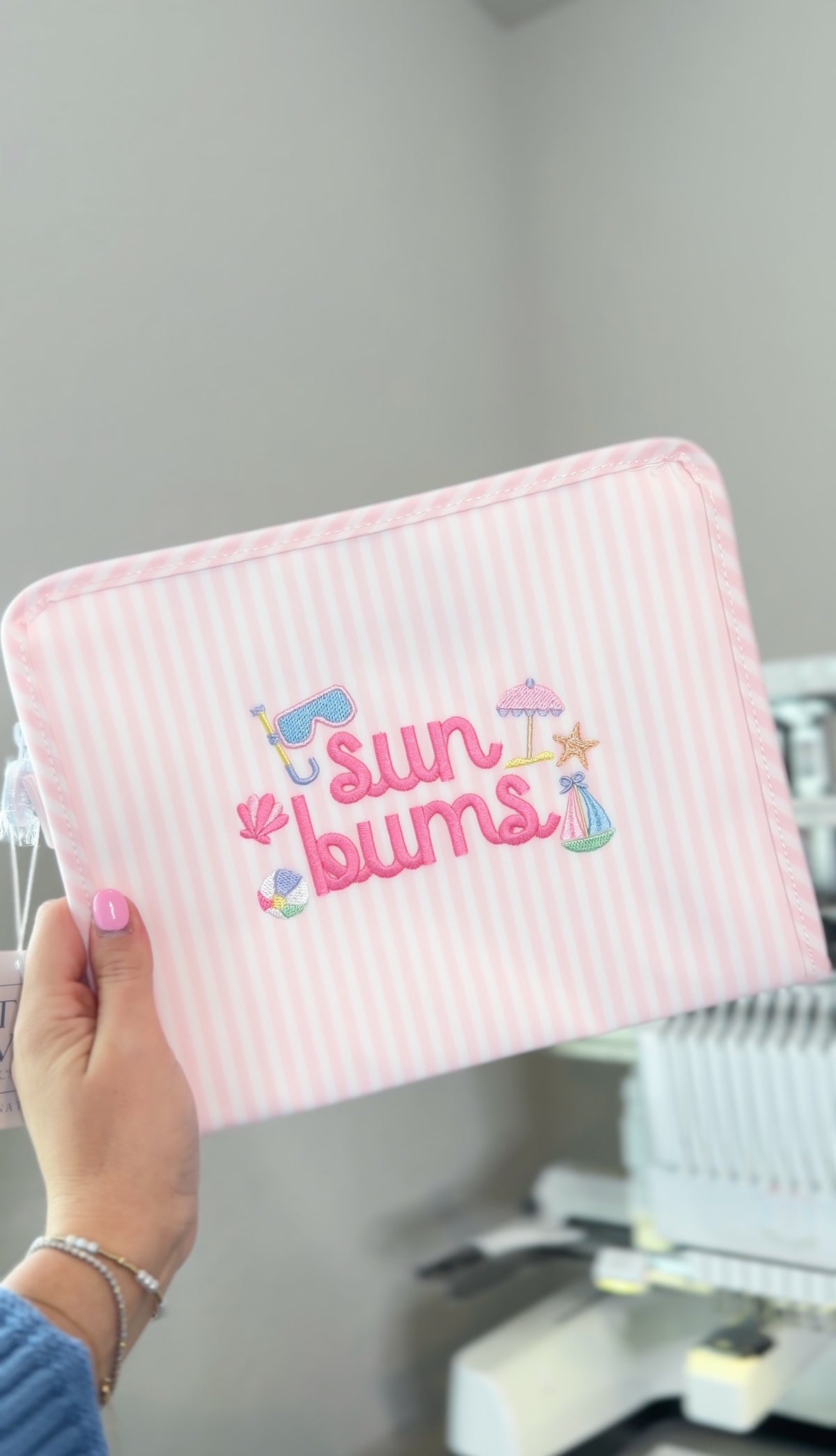 Pink Pimlico stripe TRVL Roadie pouch embroidered with 'Sun Bums' and beach icons