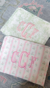 Two personalized pink ribbon floral roadie pouches with monogram embroidery
