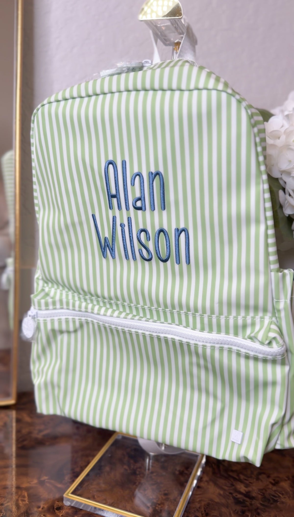 Green and white striped TRVL Backpacker on a stand, embroidered with the name 'Alan Wilson'