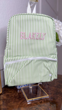 Green and white striped TRVL Backpacker on a stand, embroidered with the name 'Blakely' in pink