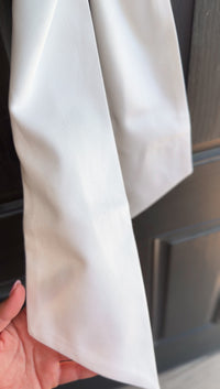 White fabric held by a hand with a blurred background