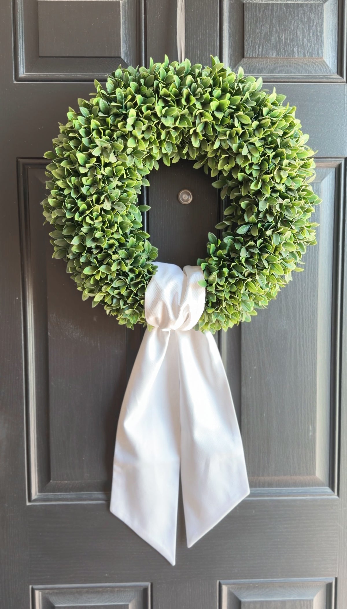 Green wreath with a white ribbon on a gray door