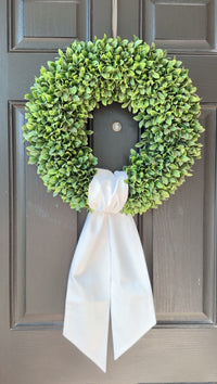 Green wreath with a white ribbon on a gray door