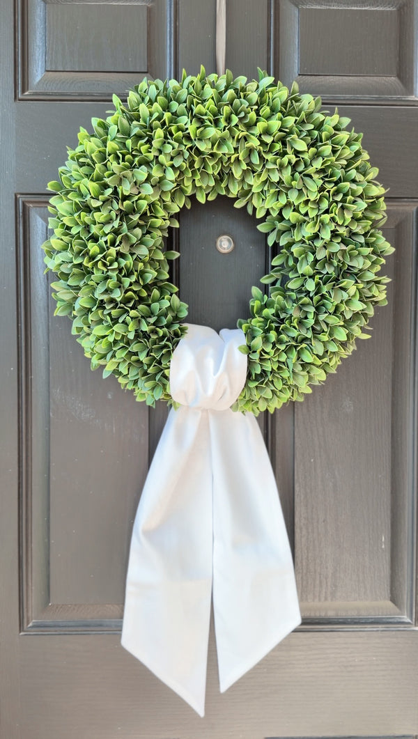 Green wreath with a white ribbon on a gray door