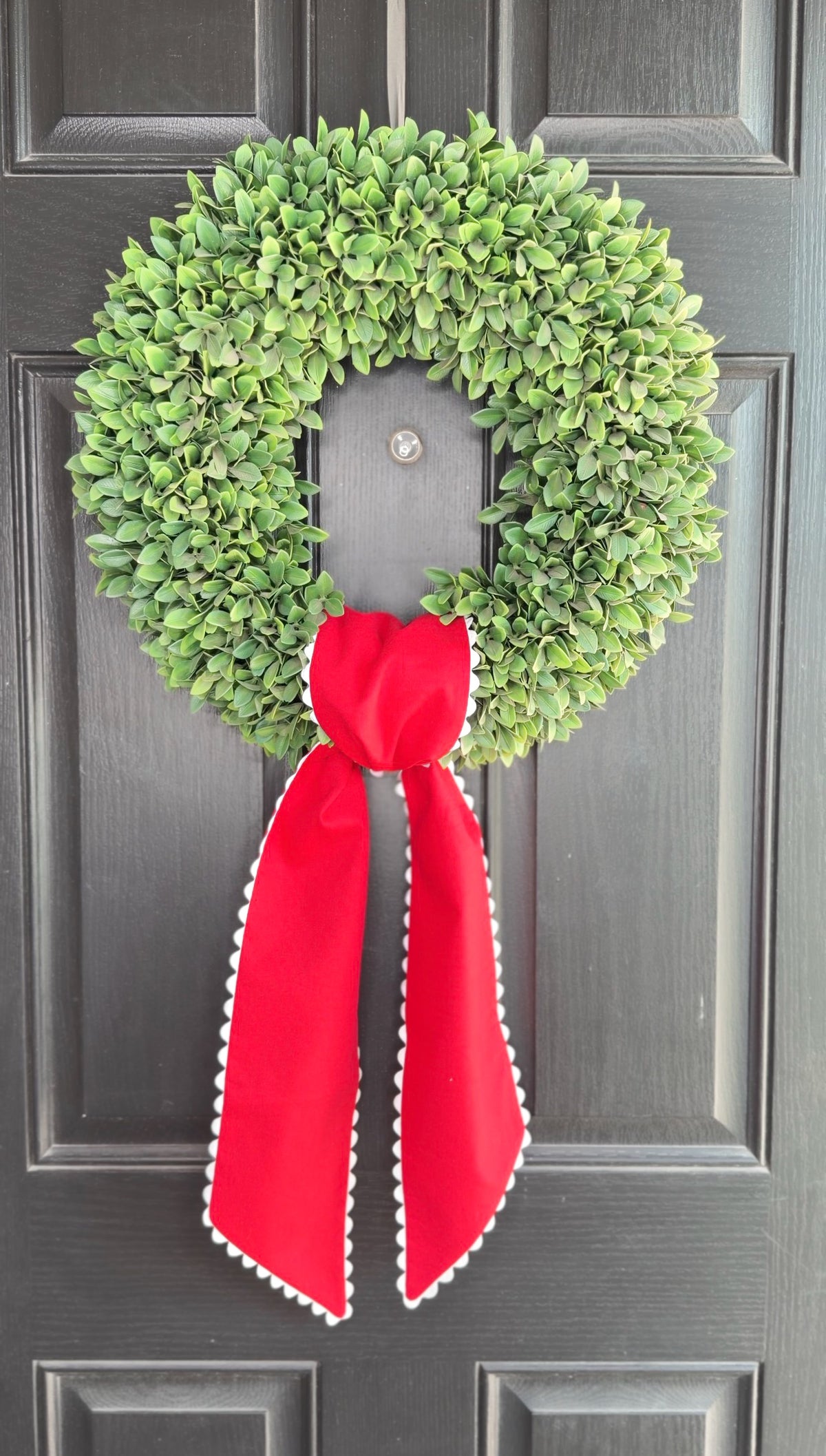 Green wreath with a red ribbon on a gray door