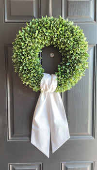 Green wreath with a white ribbon on a gray door